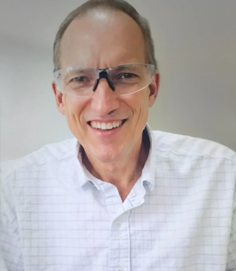 Dr. Douglas Pohl, DDS, smiling, in a white checked shirt.