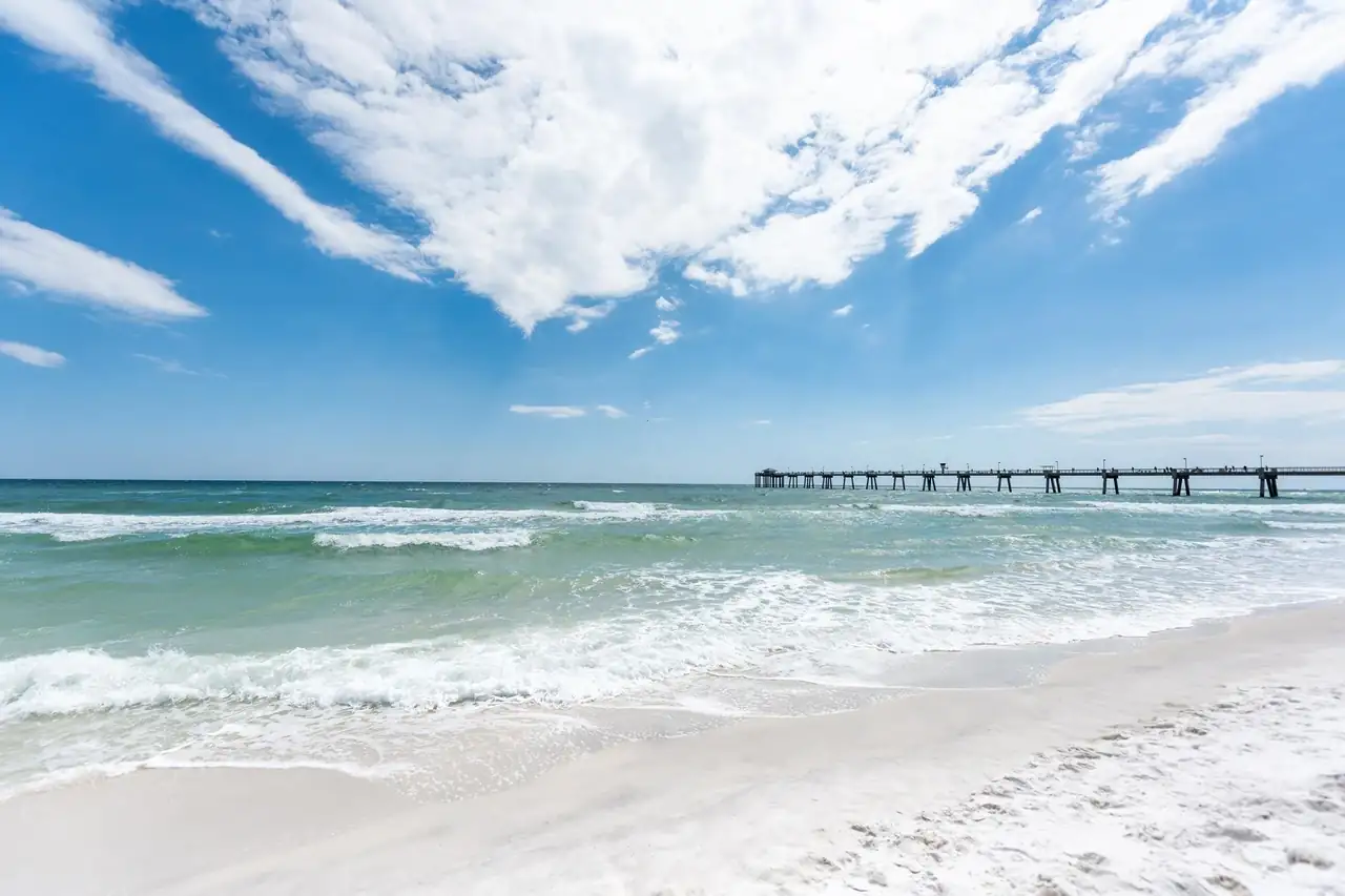 White sand, green Gulf water and a fishing pier on the Florida coast.