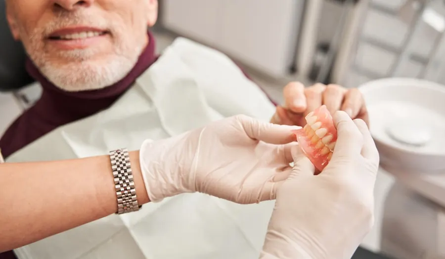 A dentist in gloves holding a partial denture.
