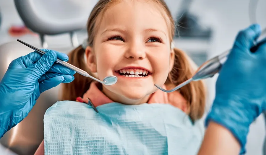 A smiling young girl in a dental chair during a checkup.
